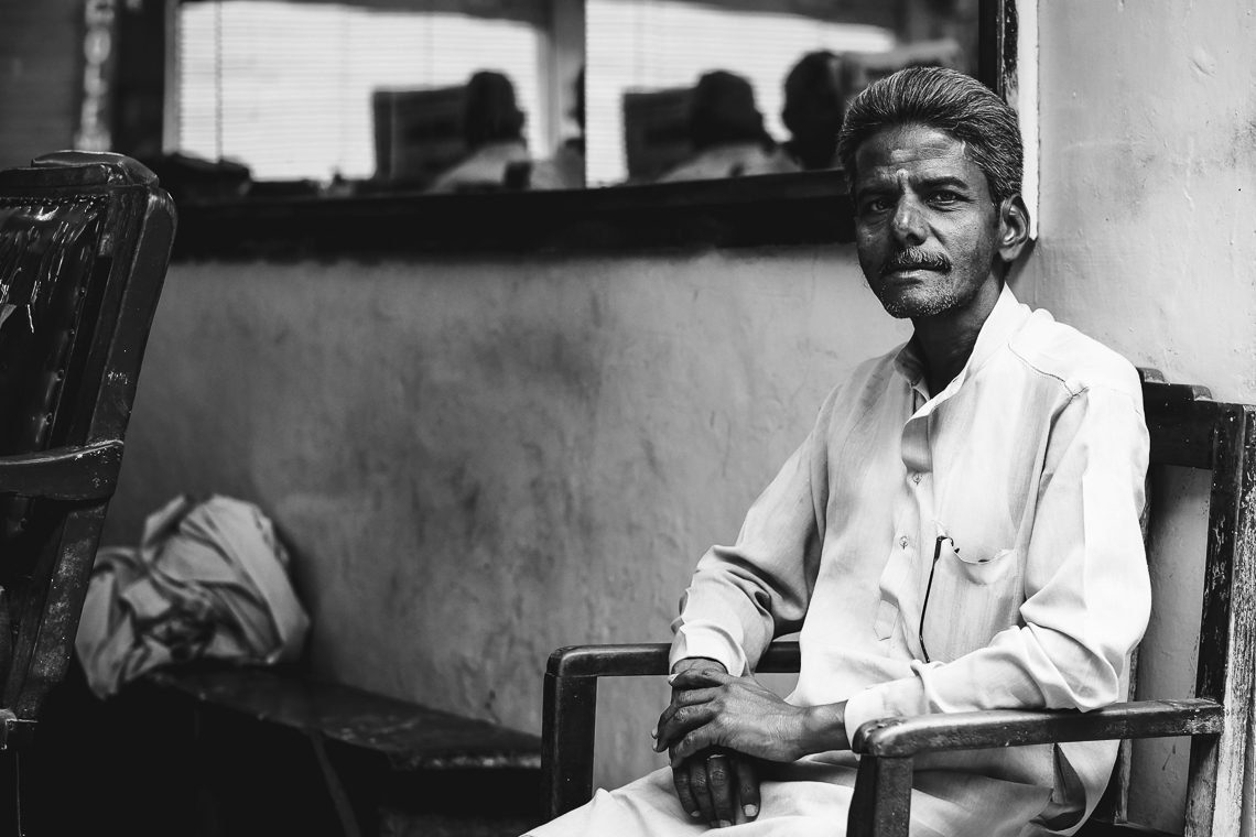 India street photography: a man waits at a barbershop in Varanasi